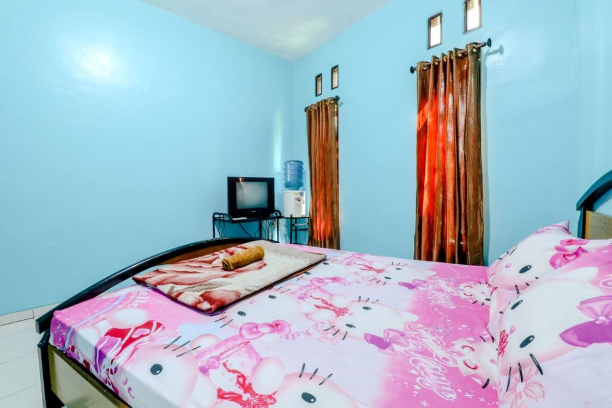 A bedroom with a bed, a TV, and curtains.