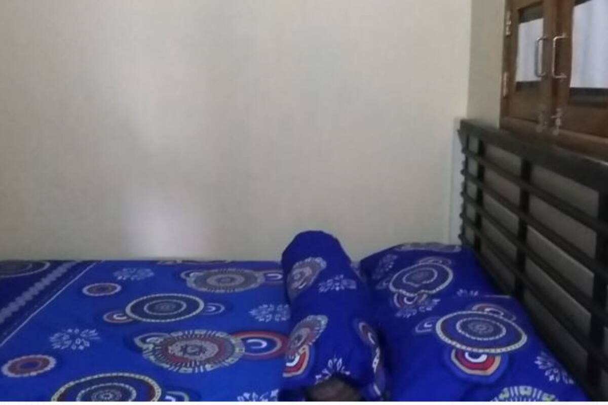 Una cama con un edredón azul estampado, un cabecero de madera y un radiador blanco.