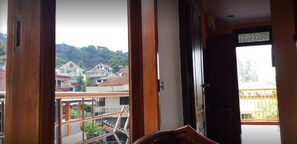 Una habitación con vista a una zona residencial, una puerta de madera y un ventanal con barandilla amarilla.