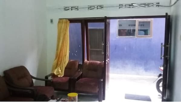 Quarto com duas cadeiras, uma mesa e uma porta deslizante para área externa.