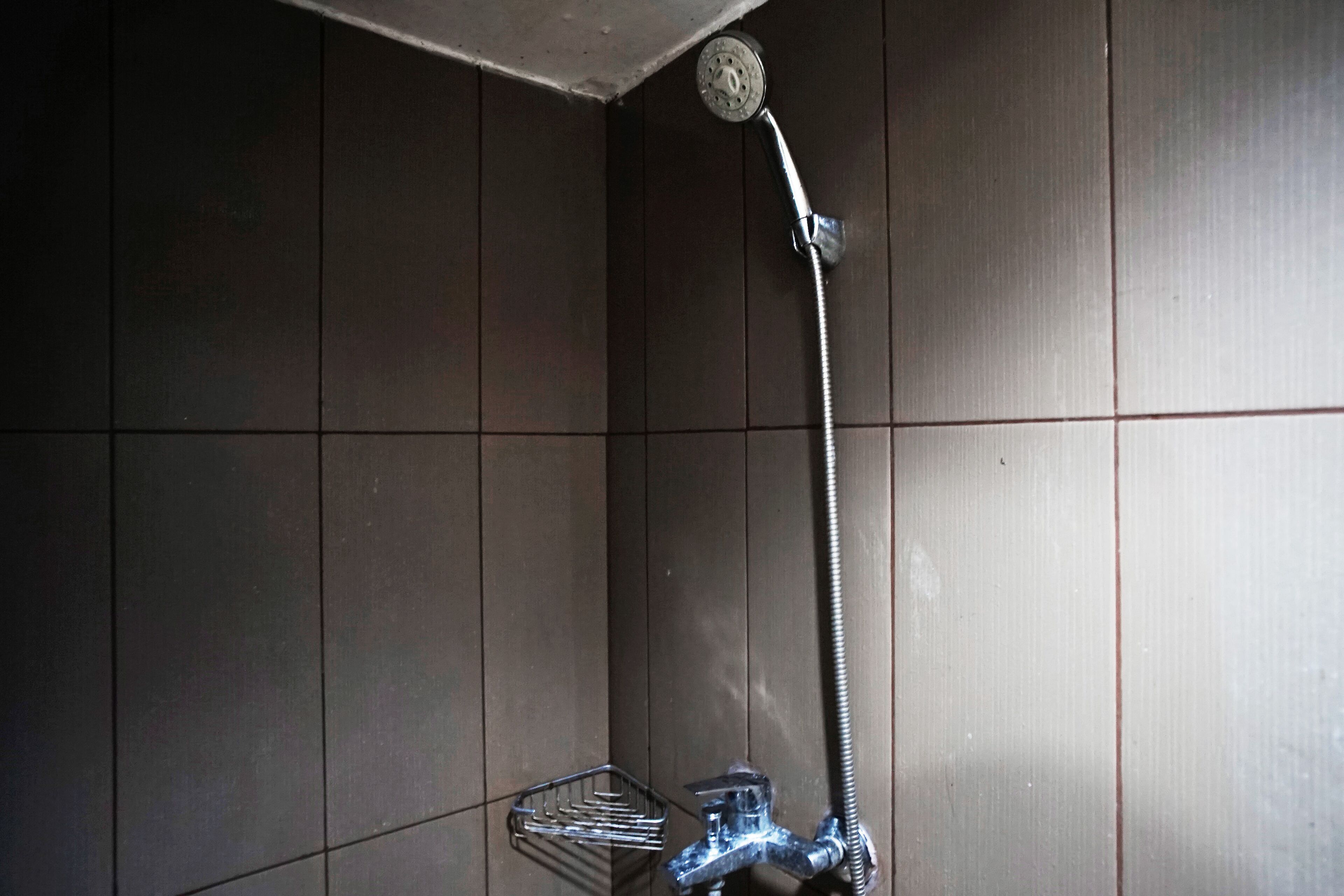A shower with a handheld showerhead and a wall-mounted faucet.