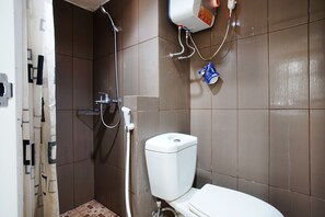Un baño con inodoro, ducha y dispensador de jabón en la pared.