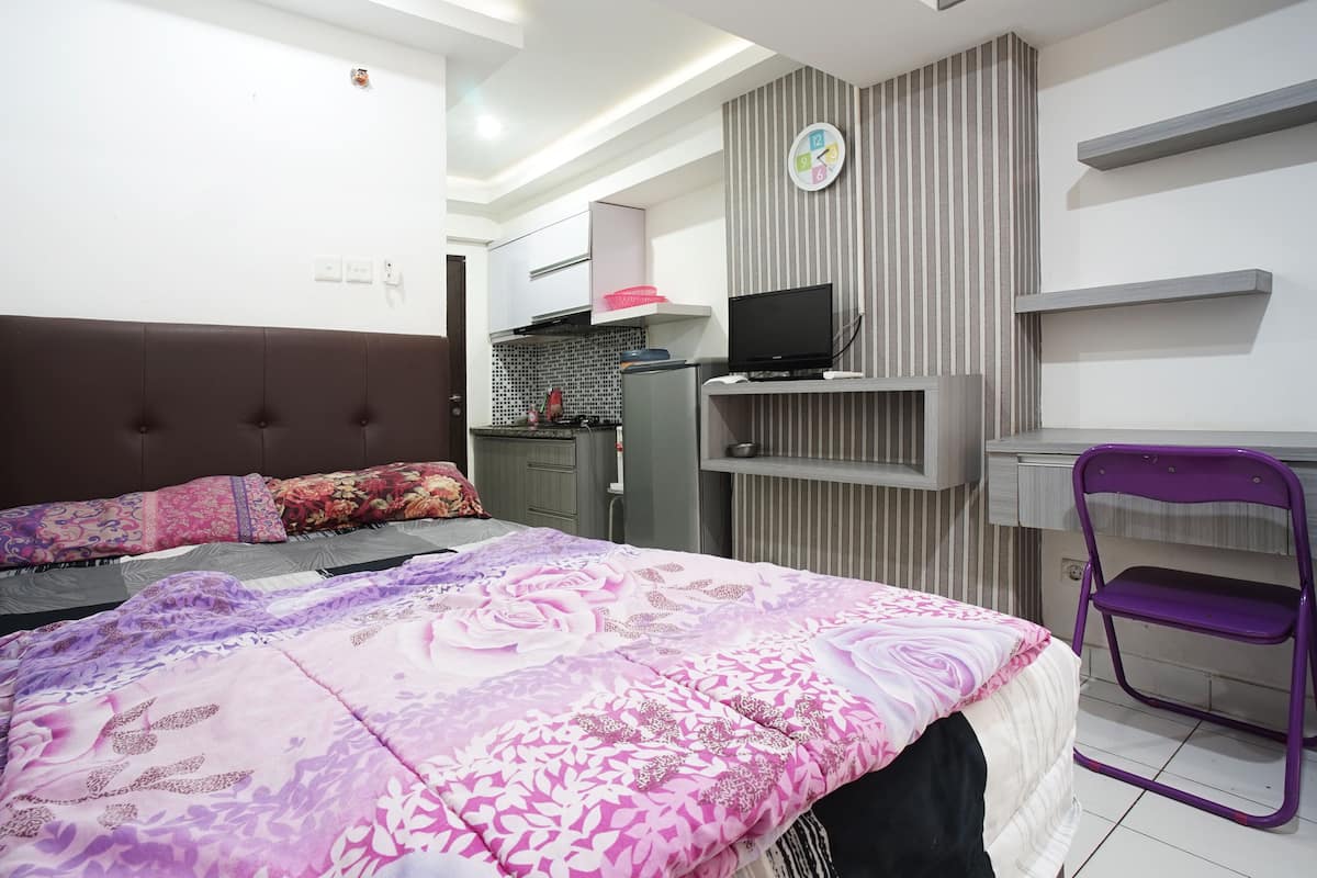 A bedroom with a bed, a desk, a chair, and a television.