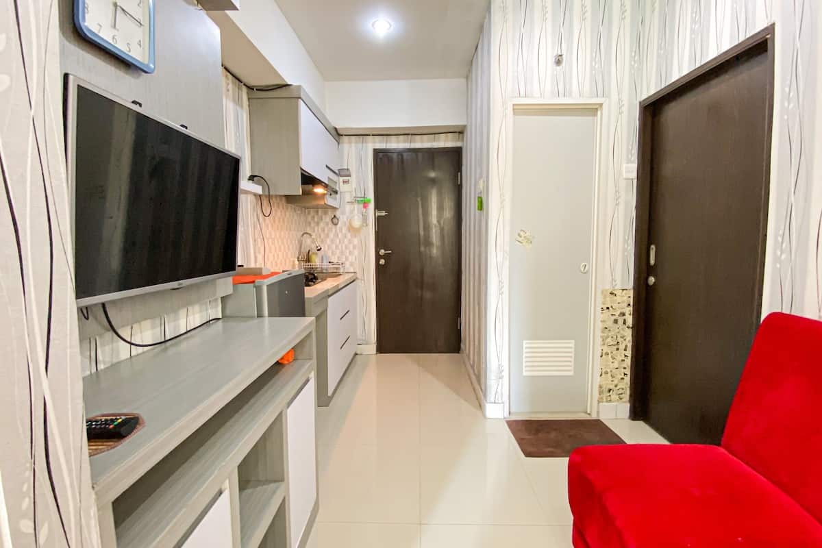 A modern kitchen with a flat-screen TV, a sink, and a red chair.
