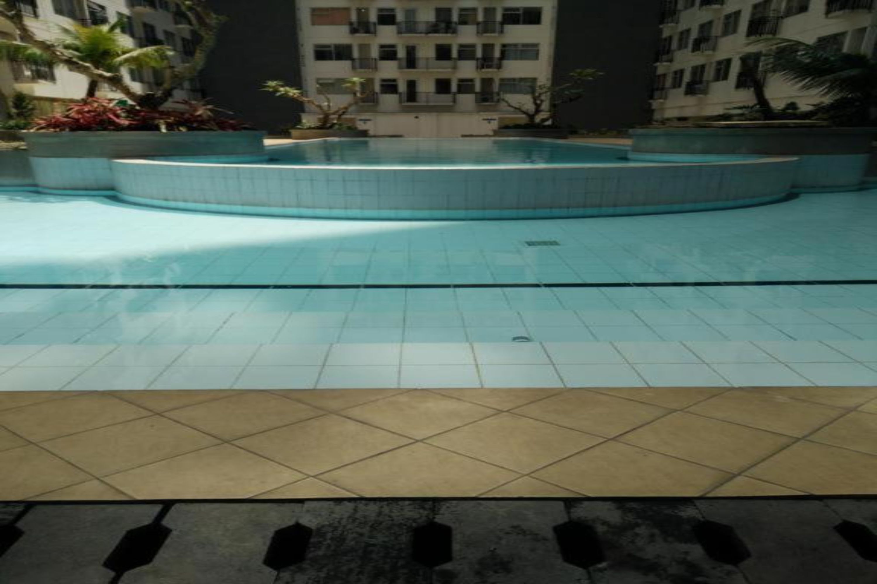 Una piscina con una zona prendisole piastrellata antistante.