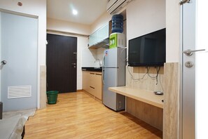 Una cocina compacta con refrigerador, dispensador de agua, microondas y un pequeño mostrador de madera.