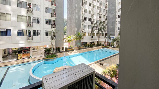 A residential building with a swimming pool, balconies, and a sign indicating a restaurant. - The Jarrdin Apartment by Tempat Singgah (Bandung)