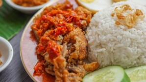 A plate of fried chicken with rice, a boiled egg, and a side of sambal.