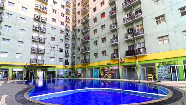 A large indoor swimming pool surrounded by a multi-story building with balconies.