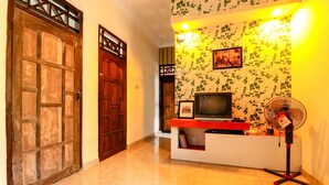 A reception area with a wooden door, a reception desk with a television, and a wall with ivy.