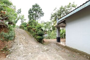 A narrow, rocky pathway leading to a building with a tiled roof and a white wall. - Jemakir Homestay (Kokap)