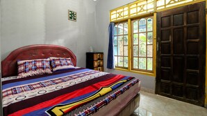 A bedroom with a bed, a nightstand, a window with a view, and a door.