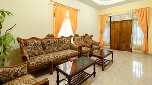 A living room with a sofa set, a glass coffee table, and a wooden door.