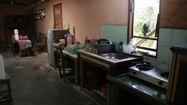 A rustic kitchen with a sink, stove, and various cooking utensils. - Sarjuni Homestay - Hostel (Kokap)