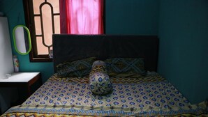 A room with a bed, a nightstand, a mirror, and a window with curtains. - Sarjuni Homestay - Hostel (Kokap)