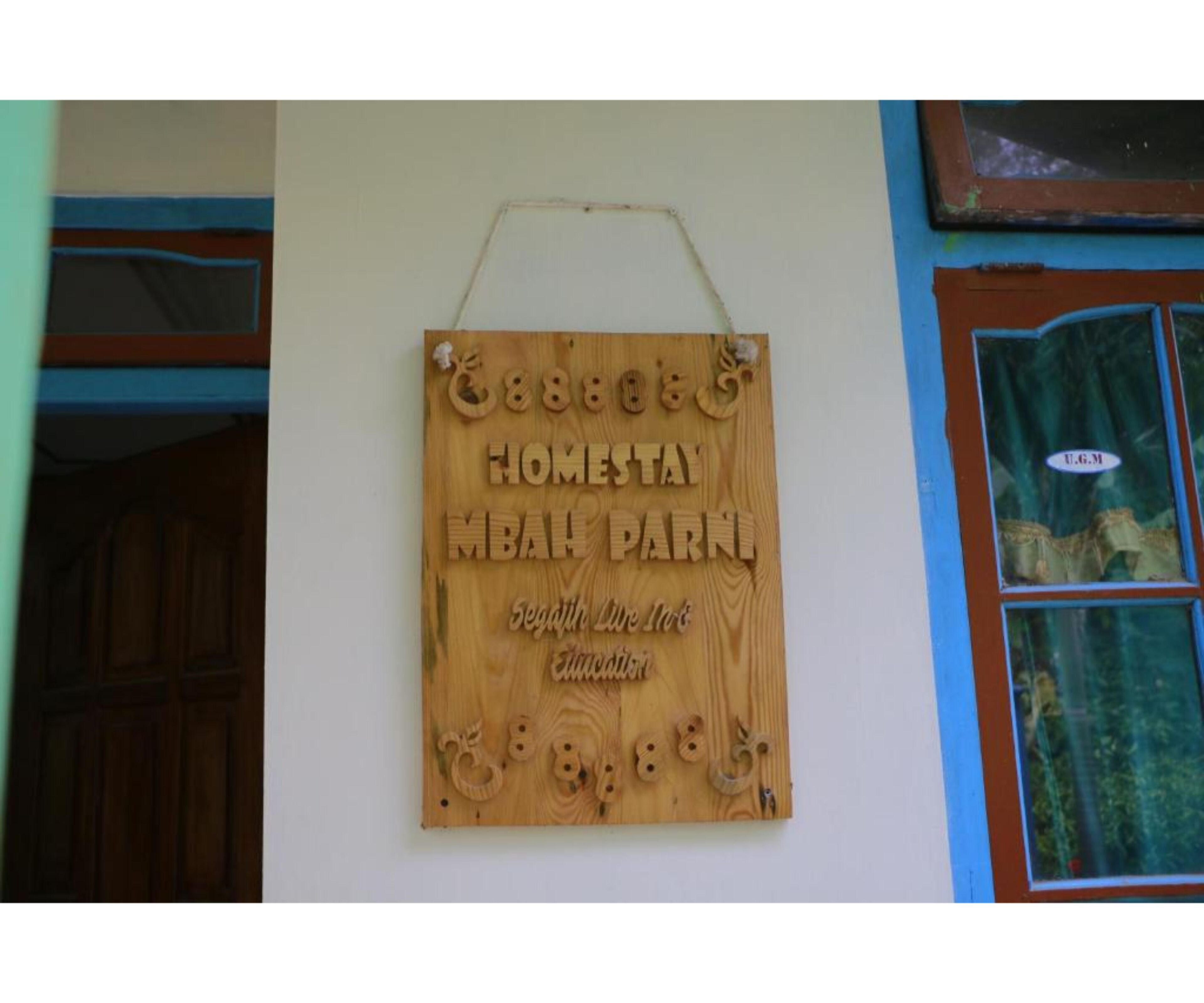 A wooden sign with the text "Homestay MBAN PARK" and "Segafredo Pizzeria" on a wall.