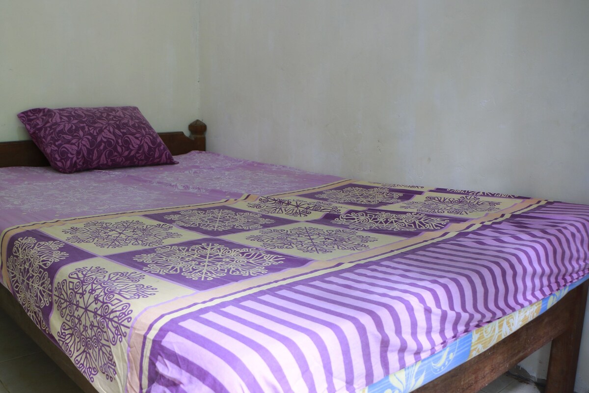Uma cama de solteiro com um edredom roxo e branco estampado e almofada combinando.