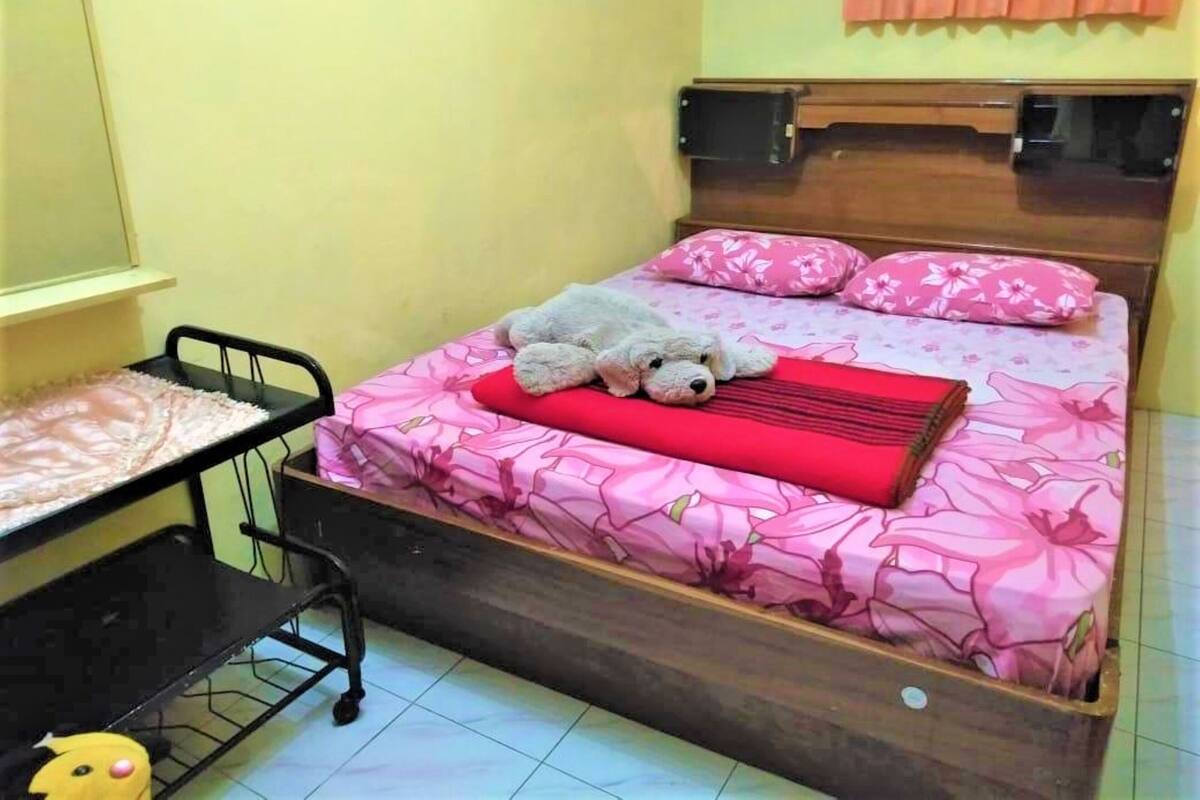 A small, tidy bedroom with a bed, a desk, and a chair.