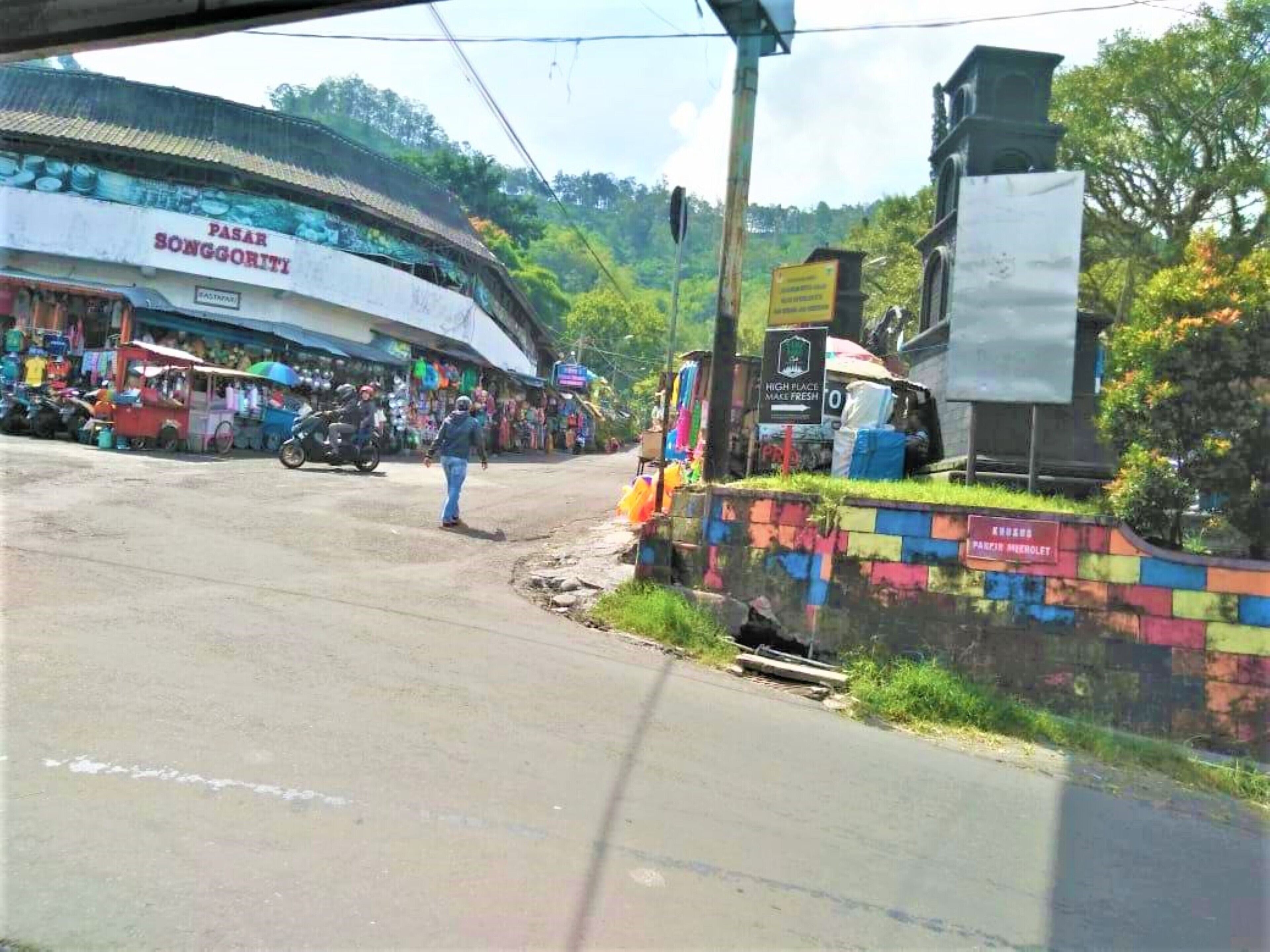 A street scene with a building labeled 'PASAR SONGGORITI' and a colorful wall with a sign 'KULING PARZIN MENOLET'.