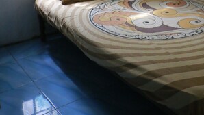 A bedroom with a bed, a window with a floral curtain, and a tiled floor. - Suparman Homestay - Hostel (Kokap)