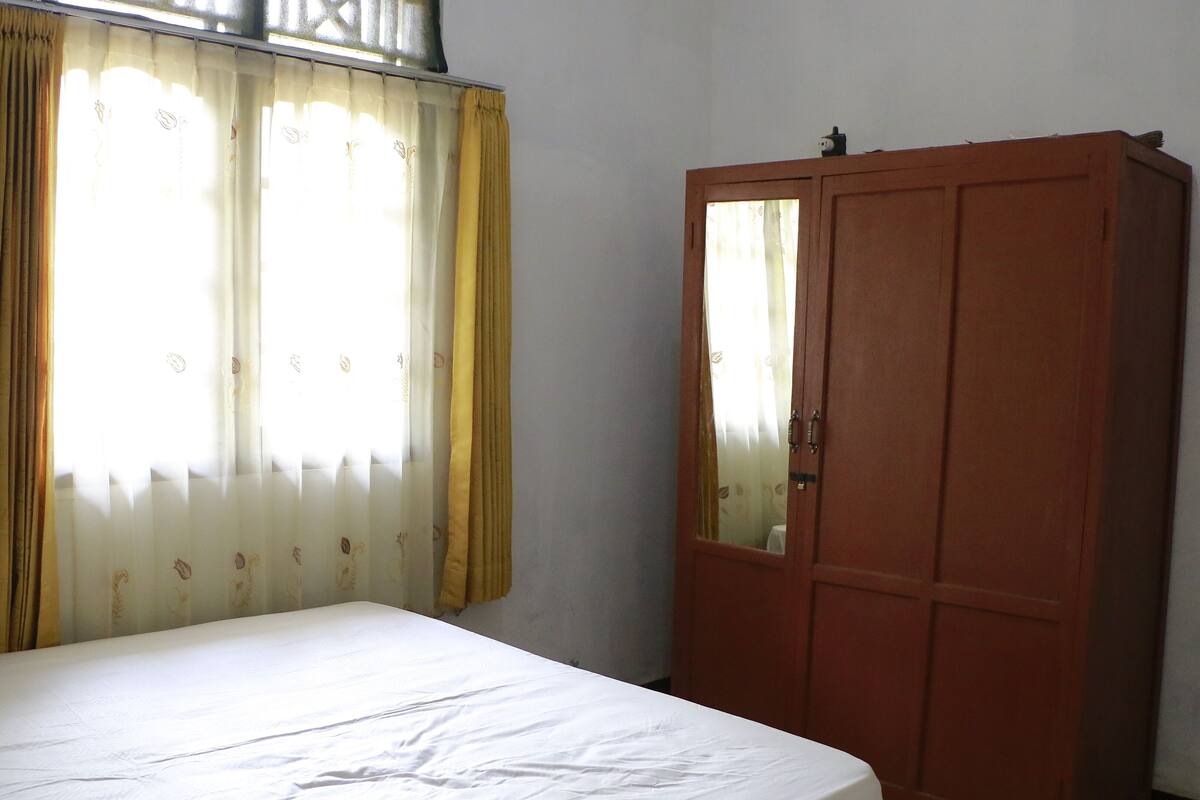 A room with a bed, a wardrobe, and curtains.