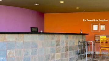 A reception area with a stone counter, a drop box, and a seating area with a chair and stools.