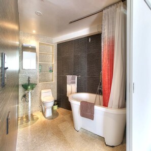 Un baño moderno con lavamanos de vidrio, inodoro y bañera.