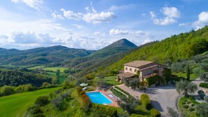 Una villa con piscina, rodeada de exuberante vegetación y montañas.