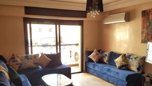 Ein Wohnzimmer mit einem blauen Sofa, einem runden Couchtisch und einer Deckenleuchte.