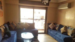 Ein Wohnzimmer mit zwei blauen Sofas, einem Couchtisch und einem großen Fenster mit Blick nach draußen.