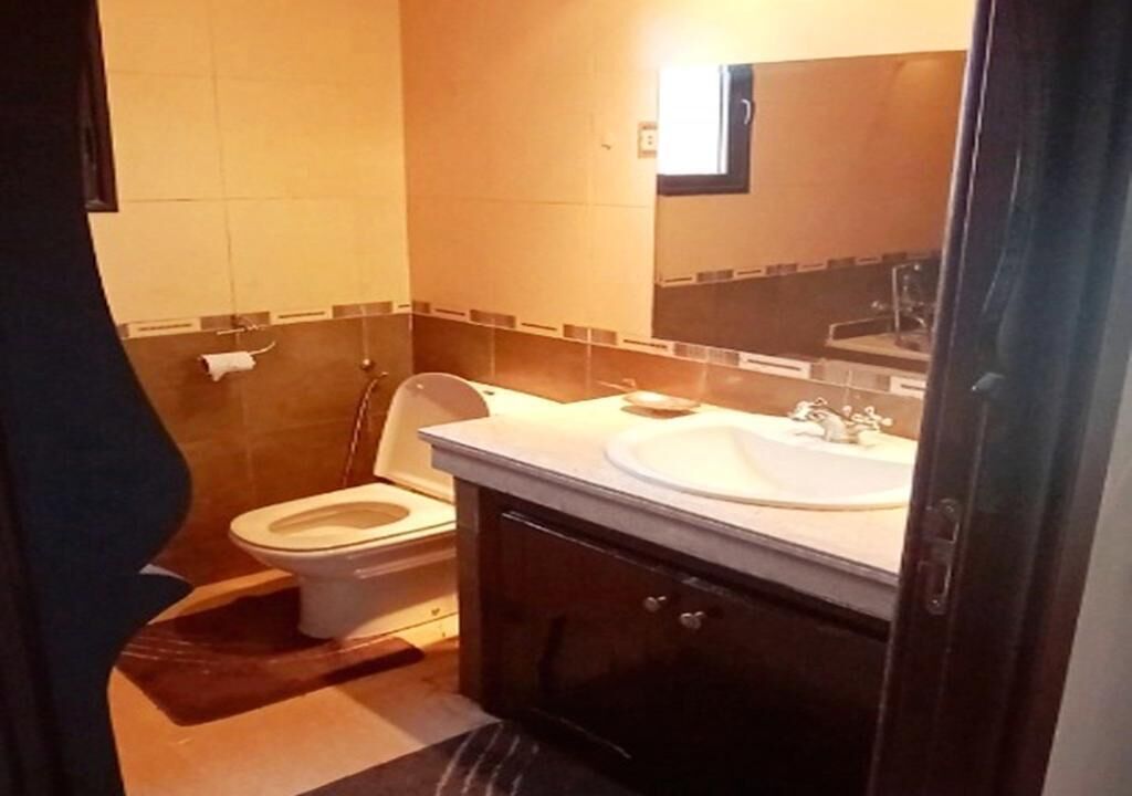 A small bathroom with a toilet, sink, and mirror.