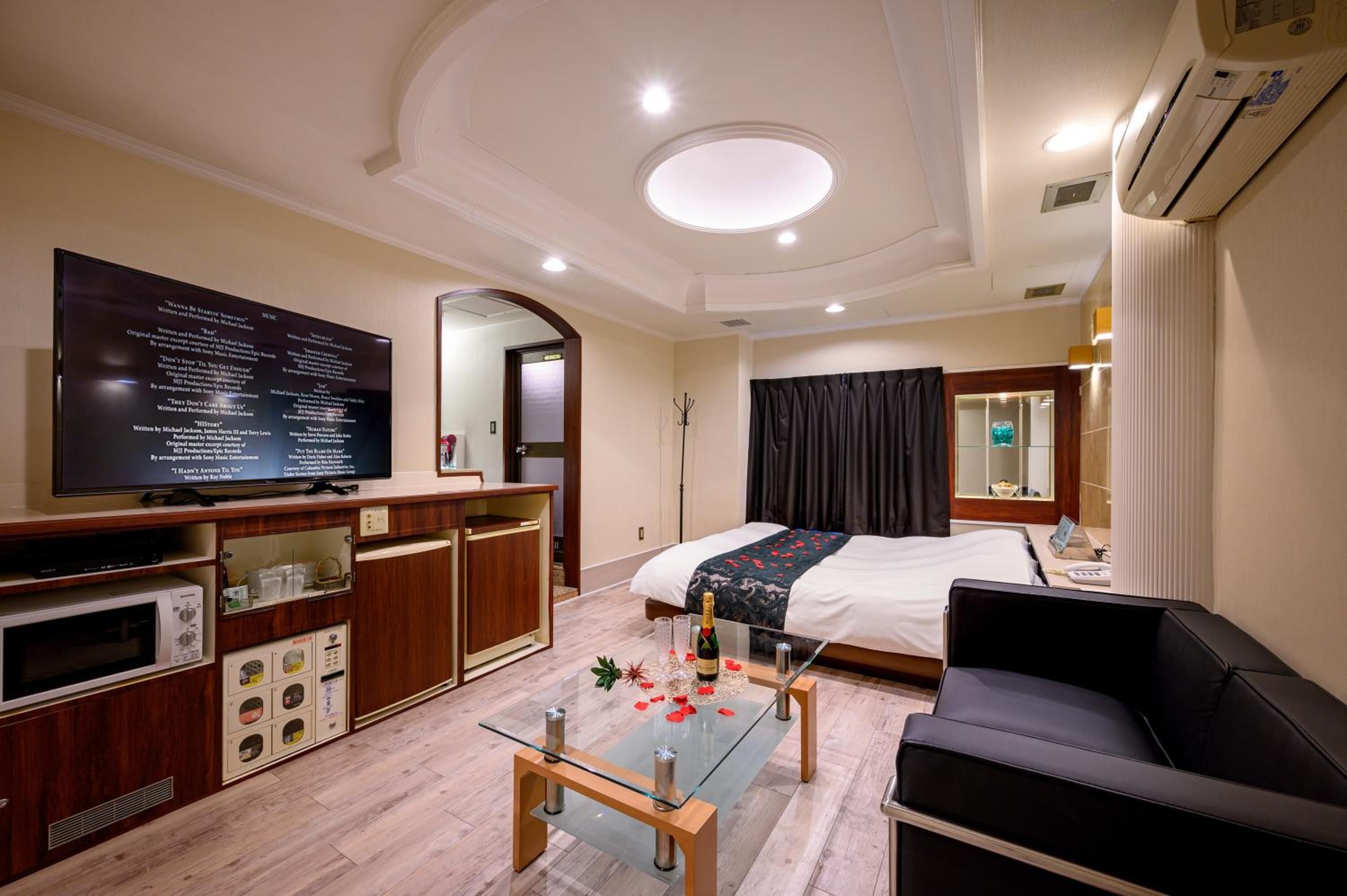 A hotel room with a bed, a TV, a desk, a glass coffee table, and a sofa.