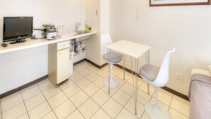 Une cuisine compacte équipée d’un téléviseur, d’un évier et d’un coin repas.