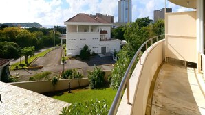 A residential building with a tiled roof, a parking lot, and a view of a tall building in the background. - Pia Resort Hotel Corner Studio Room 3 (Tamuning)