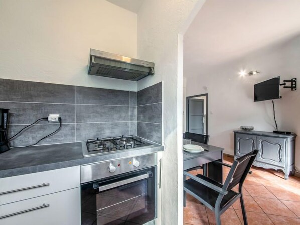 A compact kitchen with a gas stove, oven, and a small dining area with a table and chairs.