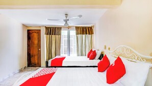 Une chambre d’hôtel avec un lit, un ventilateur de plafond, une fenêtre avec des rideaux et une porte.