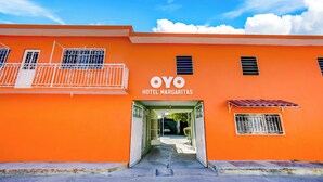 Un bâtiment de couleur orange vif, portant l’enseigne « OYO HOTEL MARGARITAS », et une entrée fermée par un portail.