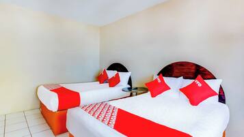 Una habitación de hotel con dos camas, cada una con ropa de cama roja y blanca, y una mesita redonda entre ellas.