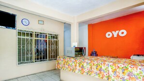 Un espace d’accueil avec une table aux motifs colorés représentant des fruits, une horloge et un mur orné du logo OYO.