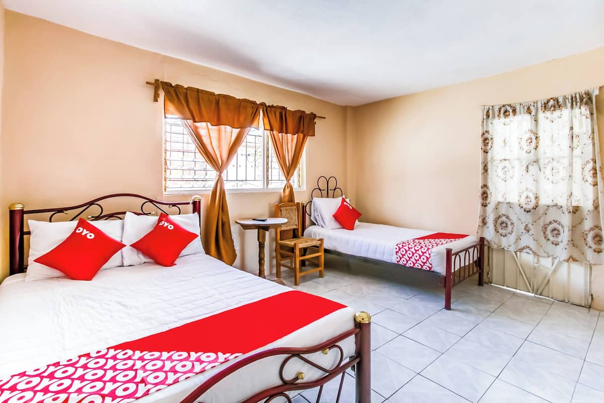 A hotel room with two beds, a small table, and a chair.