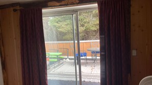 A room with a sliding glass door leading to an outdoor patio area with a wooden deck, green and blue chairs, and a table. - great for kids - pets welcome - self check in - downtown - kitchen and laundry (Idaho Falls)