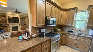 A kitchen with wooden cabinets, a gas stove, a microwave, and a coffee maker. - Walla Walla Wine Country Estate (Walla Walla)