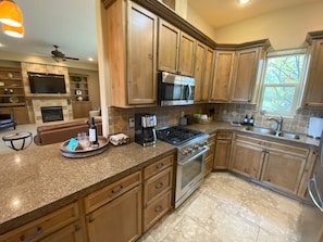A kitchen with wooden cabinets, a gas stove, a microwave, and a coffee maker. - Walla Walla Wine Country Estate (Walla Walla)