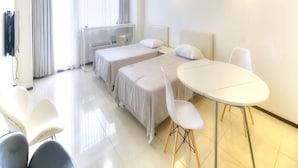 A modern hotel room with two beds, a dining table, and a seating area. - Pia Resort Hotel Standard Studio 2 (Tamuning)