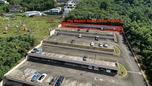 A multi-level parking structure with several cars parked, surrounded by greenery and buildings in the background. - Pia Resort Hotel Standard Studio 2 (Tamuning)