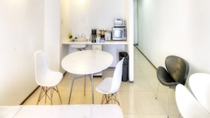 A modern kitchen with white appliances, a sink, and a dining area with white chairs. - Pia Resort Hotel Standard Studio 2 (Tamuning)