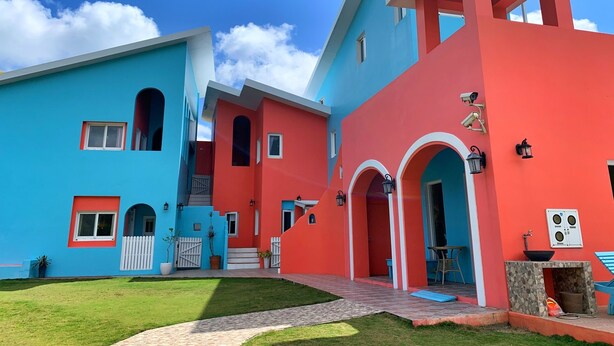 A colorful building with multiple sections, each painted in bright blue and red. There are visible windows, doors, and outdoor seating areas. - Kenting Wonderful Hotel (Hengchun)