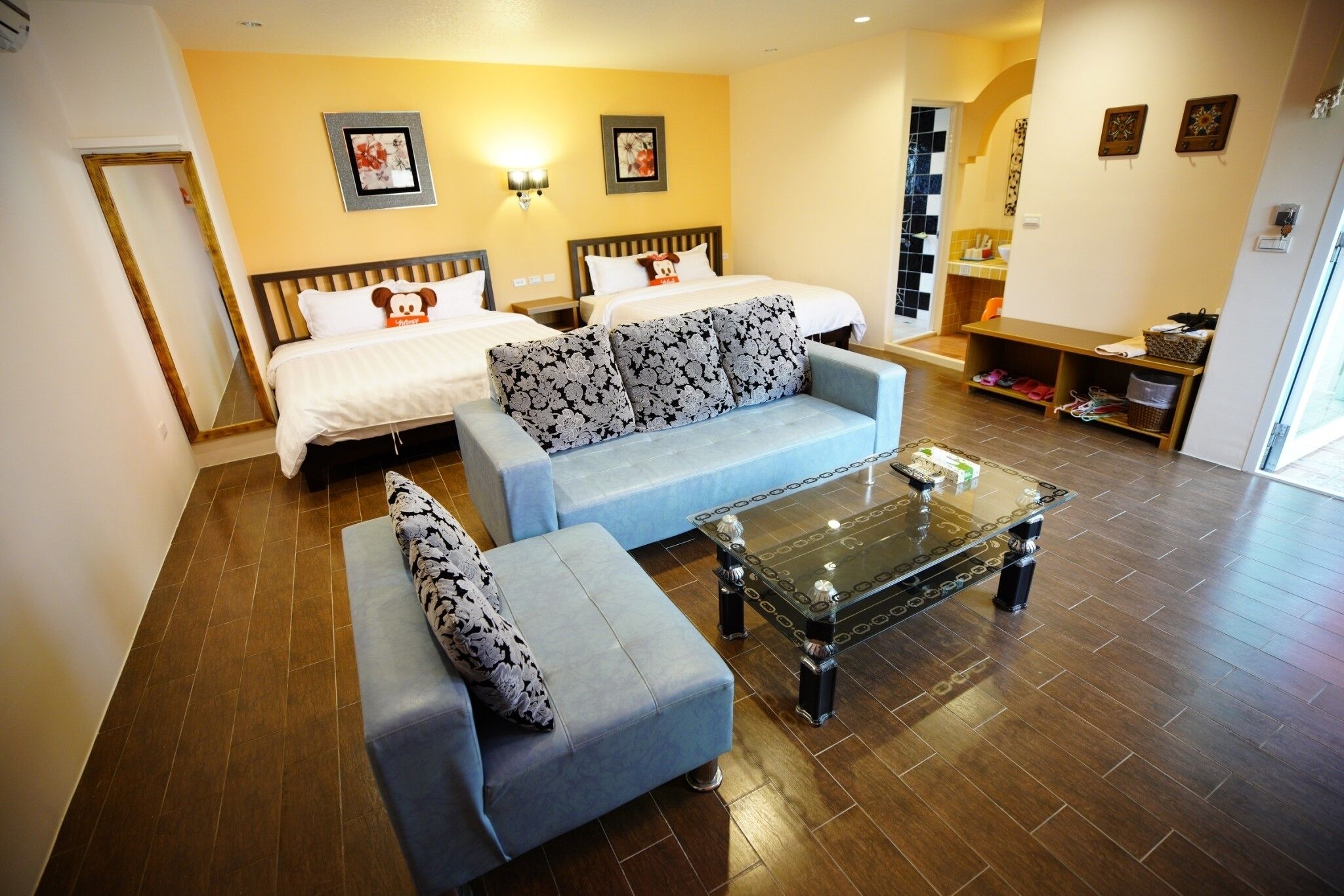 A hotel room with two beds, a sofa, a coffee table, and a small seating area.