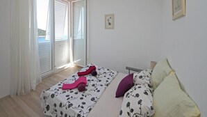 A bedroom with two beds, a large window with a view of the sea, and a small framed picture on the wall. - Apartment Lavandula - Two-Bedroom Apartment with Sea View (Dubrovnik)