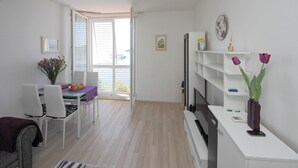 A modern, well-lit room with a dining area, a TV, and a bookshelf. - Apartment Lavandula - Two-Bedroom Apartment with Sea View (Dubrovnik)